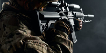 Old soldier in uniform pointing with sniper rifle.